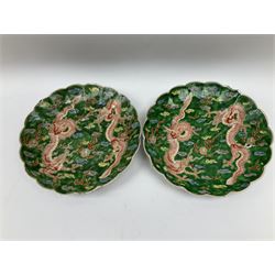 Pair of Japanese Meiji period plates, of circular form with lobed rims, each decorated with two red three clawed dragons chasing flaming pears amidst auspicious clouds, upon a green awaji type glazed ground, each with character mark beneath, D24.5cm