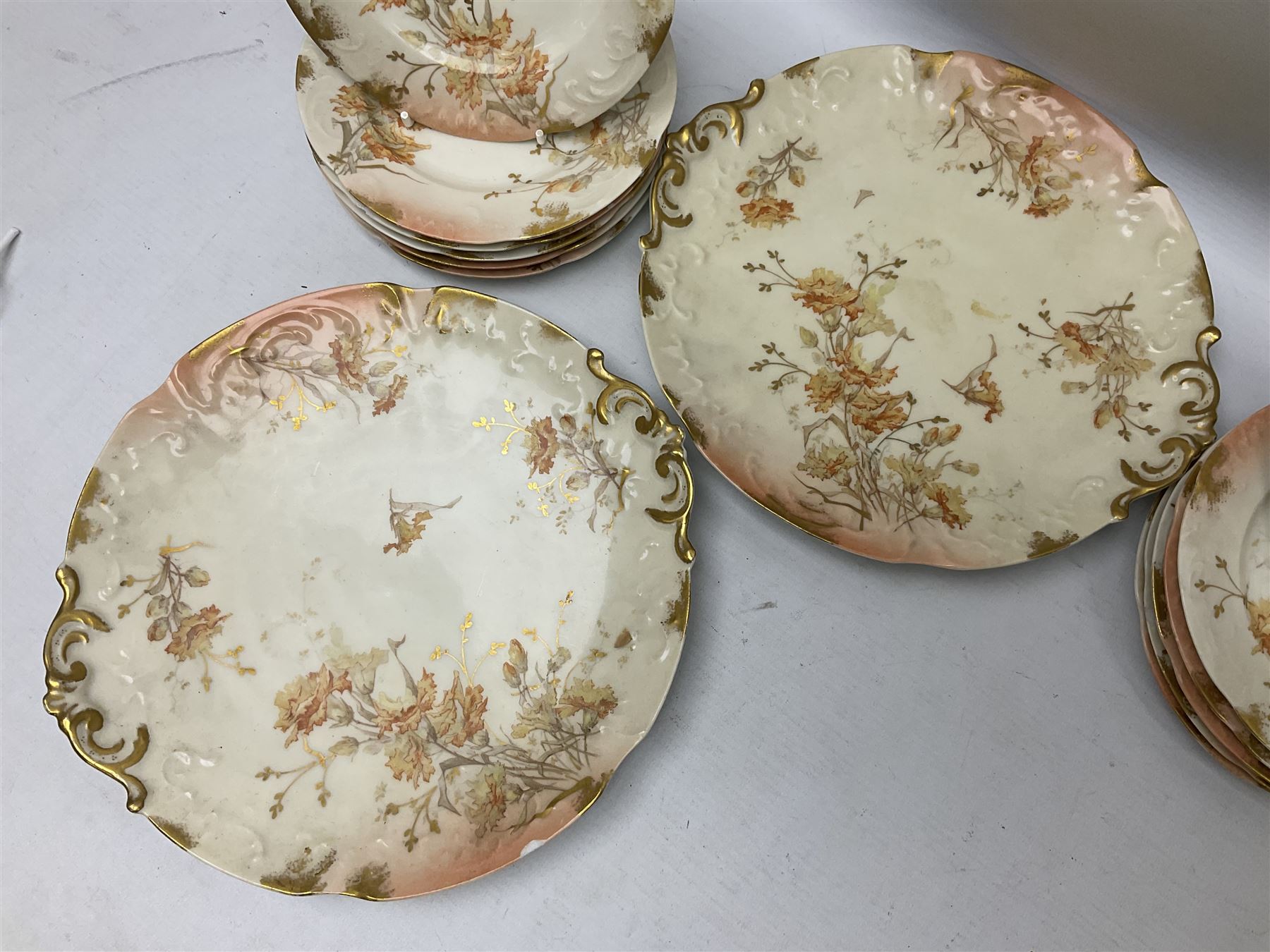 Early 20th century Limoges part tea service, decorated with floral sprays and gilt on merging peach and white ground, comprising six teacups, twelve side plates, six smaller plates, milk jug, open sucrier, slop bowl and two cake plates, many marked R Delinieres Limoges D&C France to base