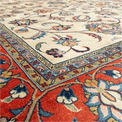 Persian Sarough carpet, ivory field with symmetrical arrangement of scrolling vines, palmettes and floral sprays in red, blue and green, enclosed by a broad red main border with repeating floral motifs, originating from the Arak region of Iran