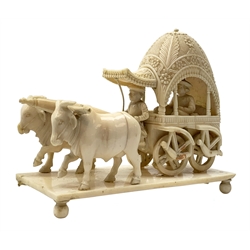 Early 20th century Indian carved ivory figure group, modelled as a foliate detailed carriage containing passenger and driver, drawn by two oxen, raised upon a rectangular base with bun feet, L11.5cm, H9.5cm