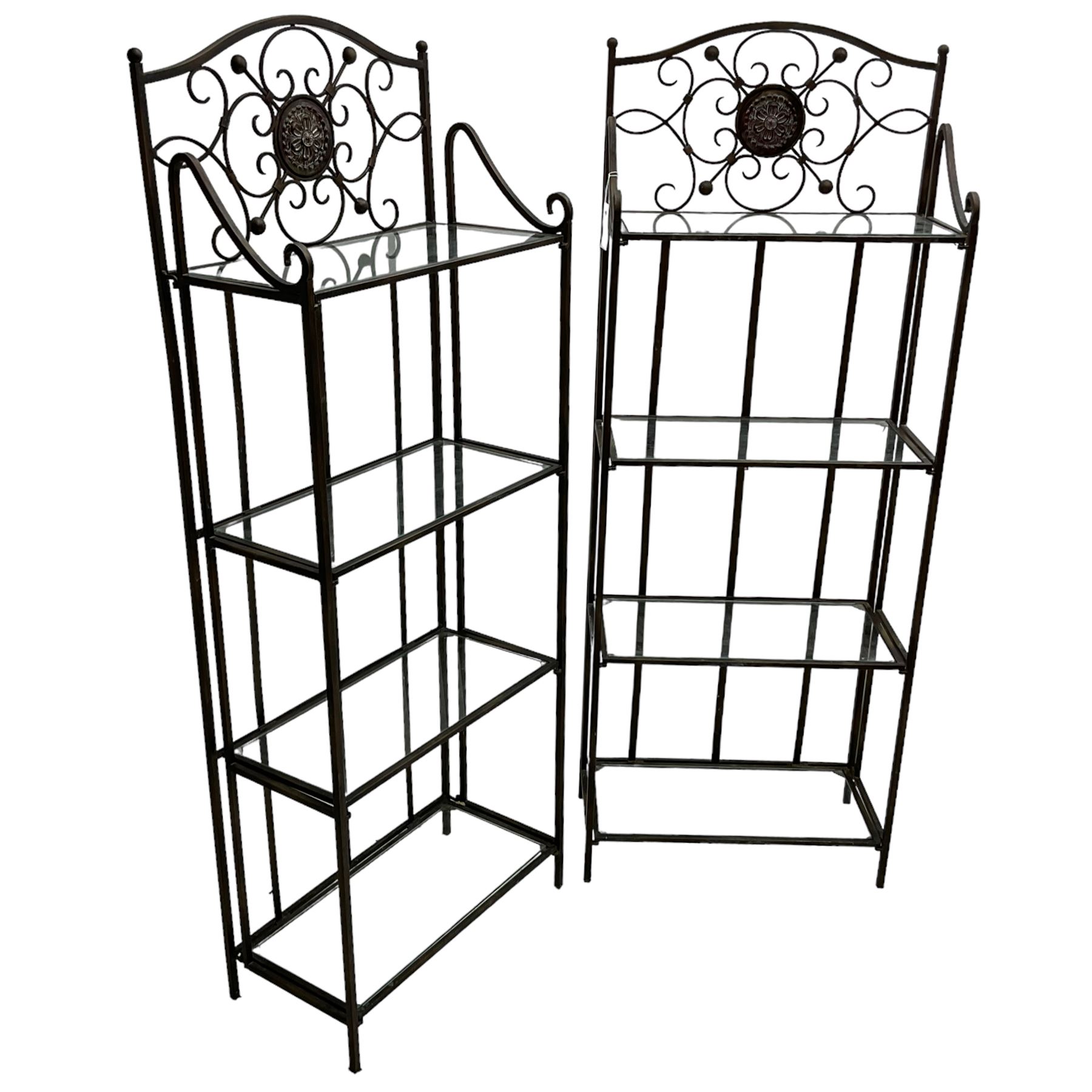 Pair of wrought metal conservatory plant stands, raised back with scrolling design, each fitted with three glass shelves