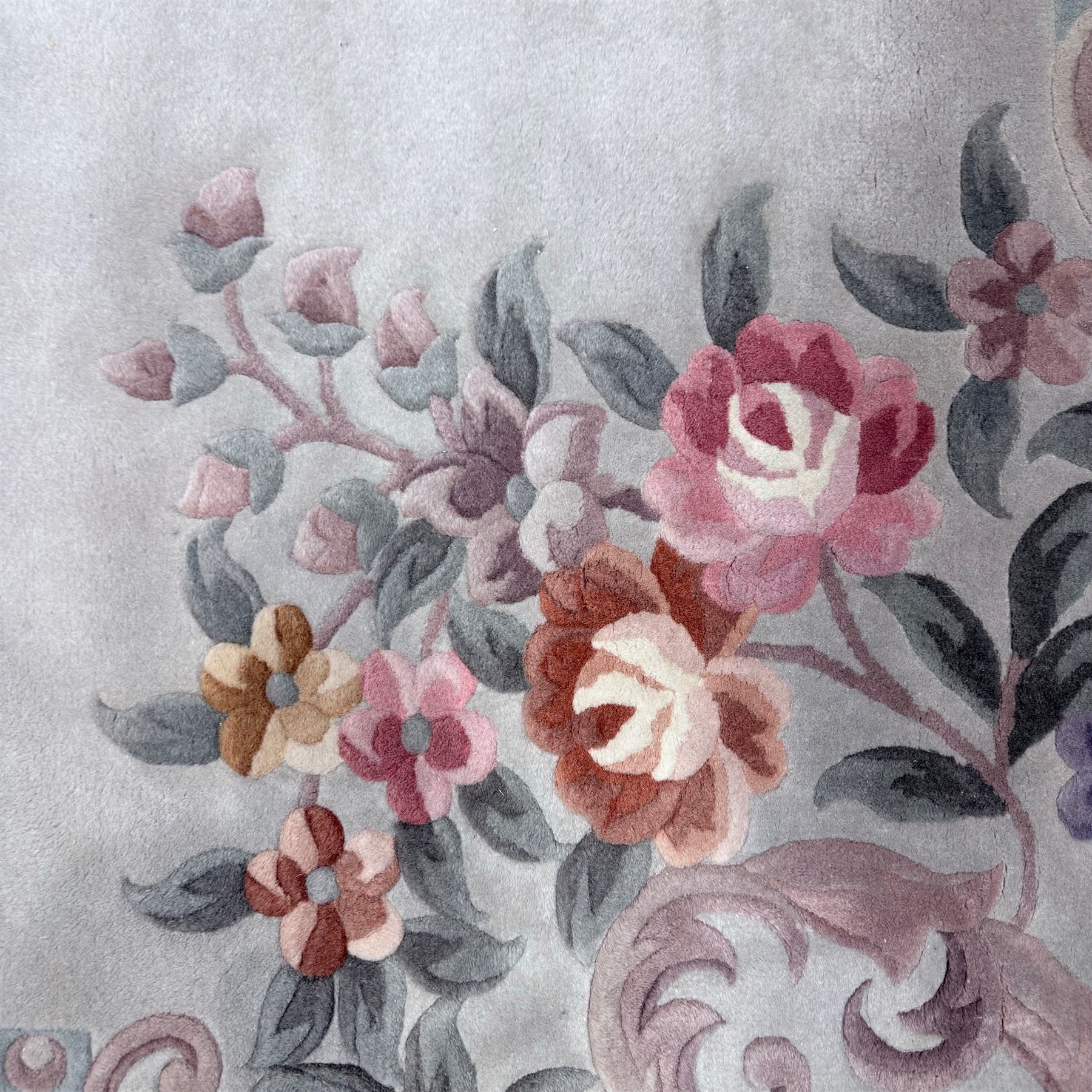 Chinese Aubusson-style jade green wool rug, with a floral medallion and floral corner sprays with a scrolling acanthus and ribbon border in tones of teal, cream, pink, mauve, and cotton fringe ends