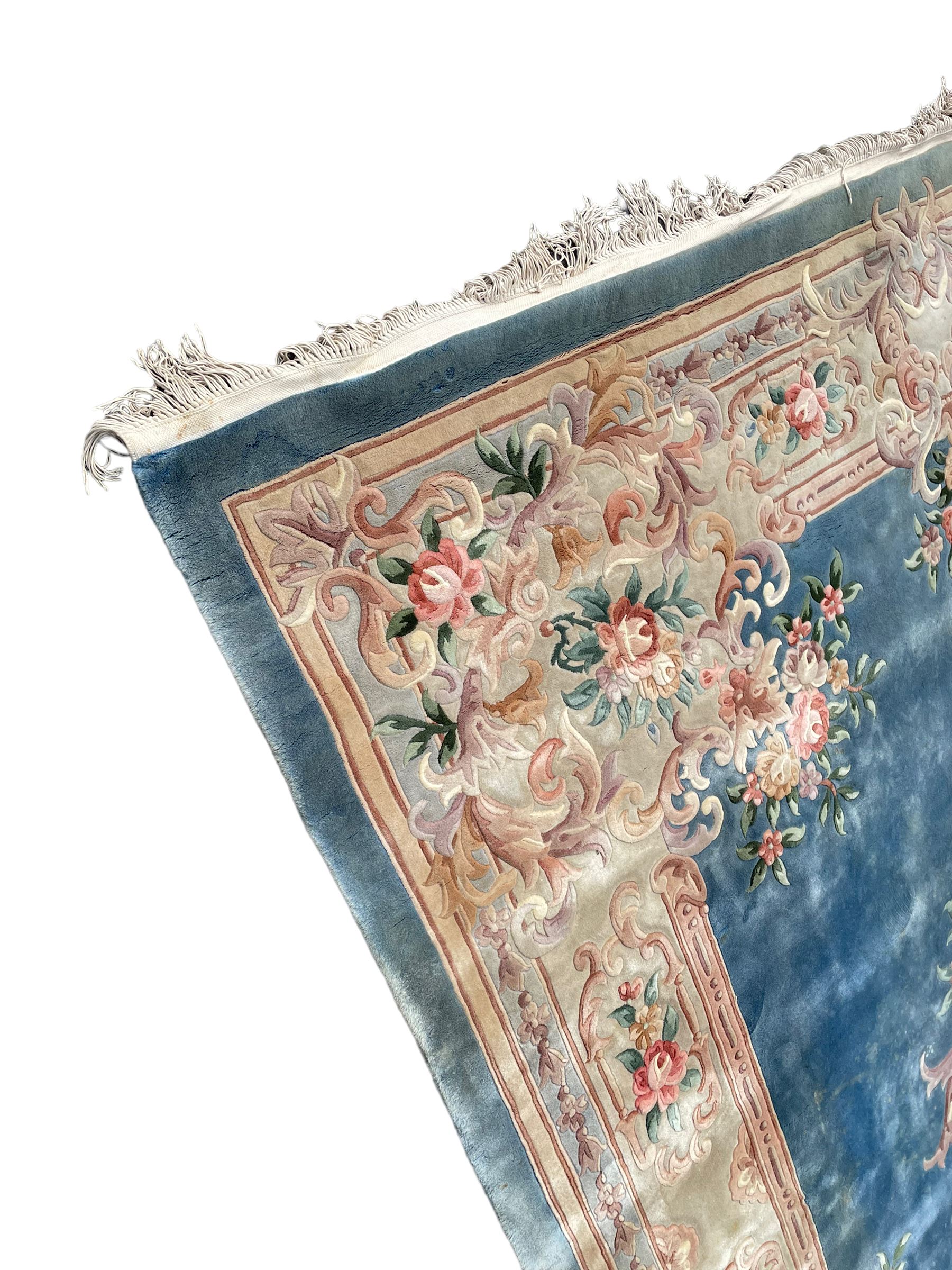 Large Chinese blue ground woollen carpet, overall floral design, central oval medallion surrounded by scrolling floral decoration, wide border with decorated with floral bouquets 