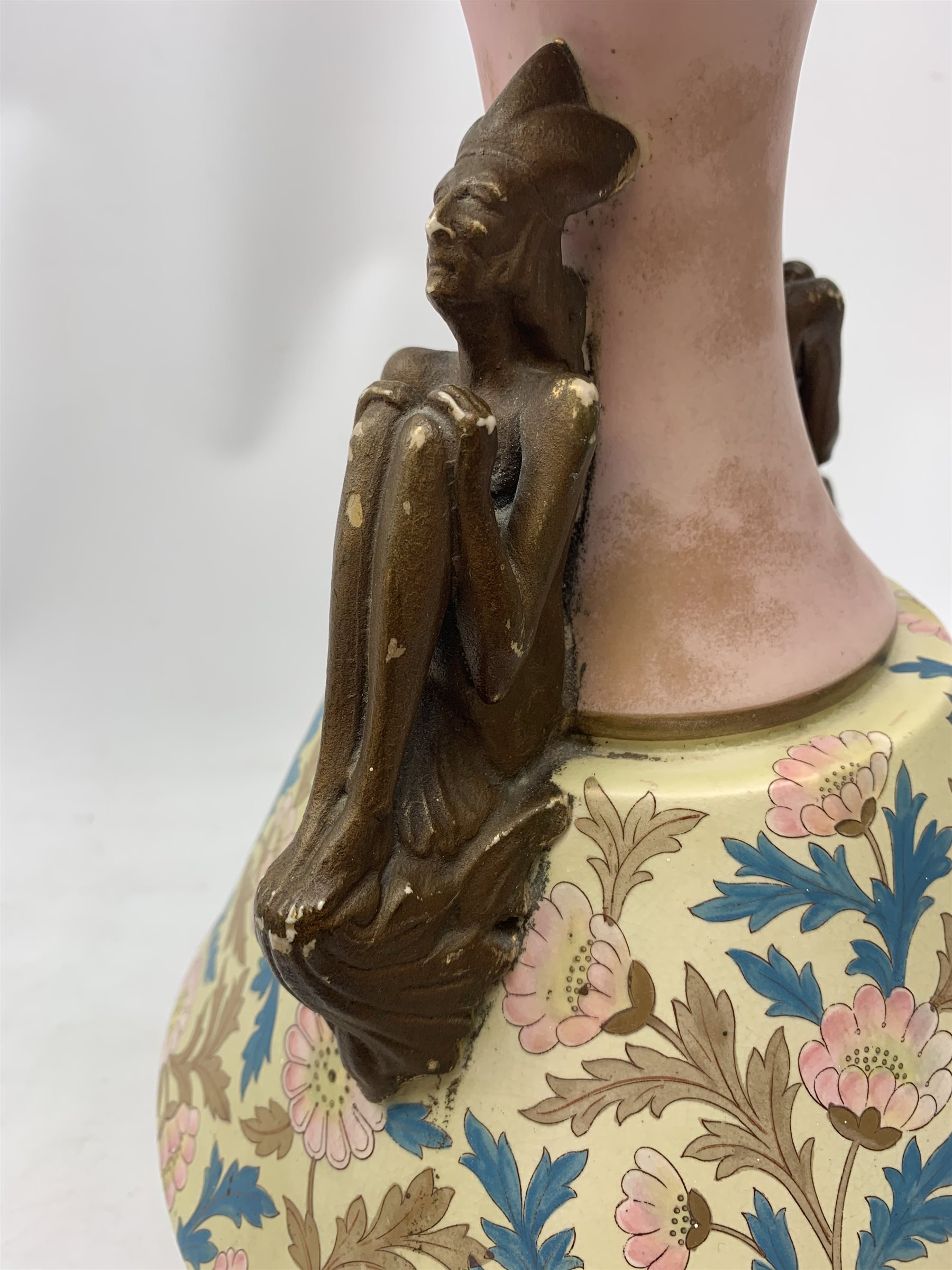 A late 19th century Aesthetic Movement Old Hall vase designed by Christopher Dresser, the flared body decorated with stylised flowering vines, leading to a tapering neck and flared rim with twin figural handles (one s/d), and raised upon a circular footed base, with printed mark beneath, H35cm. 