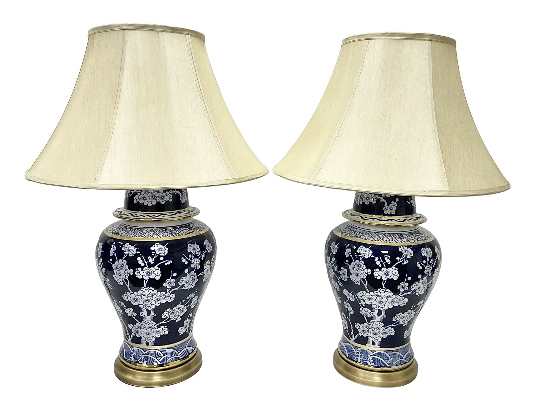 Pair of blue and white table lamps, each of baluster form, decorated with prunus blossom, within stylised borders, raised upon circular gilt base, excluding fittings H48cm