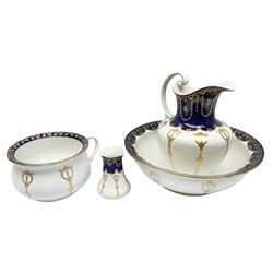 Early 20th century Bishop and Stonier four piece toilet set, comprising washbowl, wash jug, toothbrush pot, and chamber pot, each  decorated with deep blue band and husk swags and festoons in gilt, with printed Caduceus Bisto marks beneath and printed retailers mark 'Manufactured for Harrods Limited London', wash bowl D43cm, wash jug H31.5cm