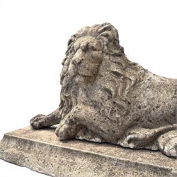Neoclassical design cast stone garden lion, modelled recumbent with raised and flowing mane, on rectangular plinth base, with flat plain reverse, in weathered finish