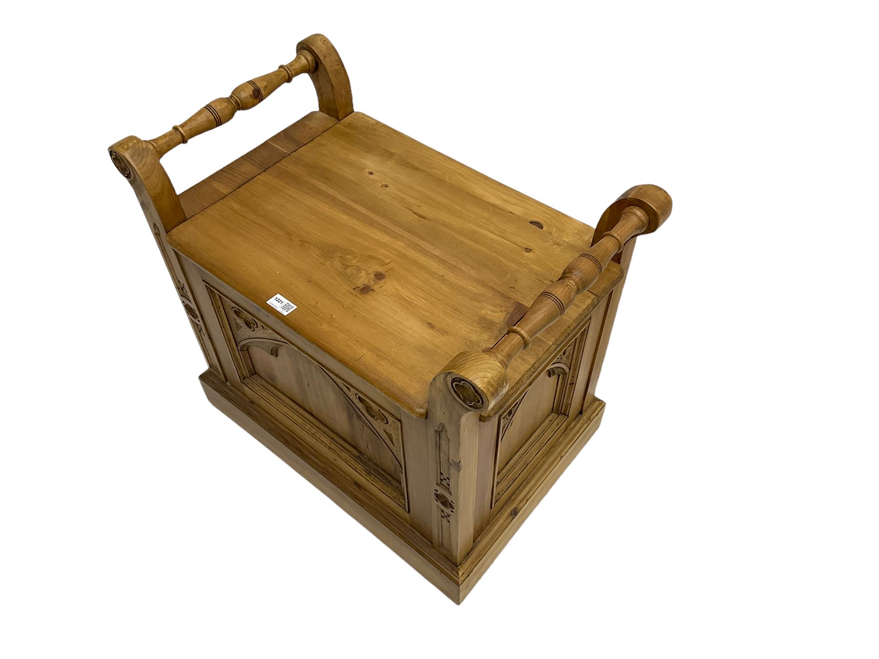 Gothic style pine stool with hinged box seat, decorated with flower head motifs, plinth base