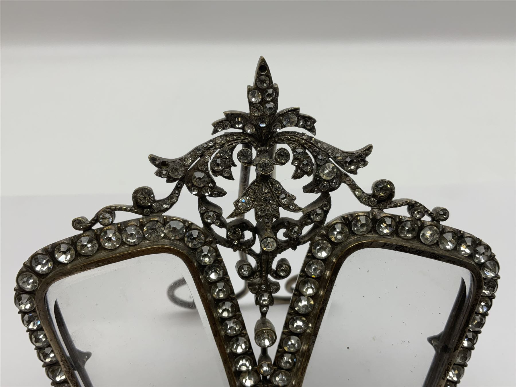Early 19th century silver plated double photograph frame, each rounded rectangular aperture surrounded by a paste border, with ornate scroll feet and mantling also set with clear paste stones, with easel style support verso, H12cm