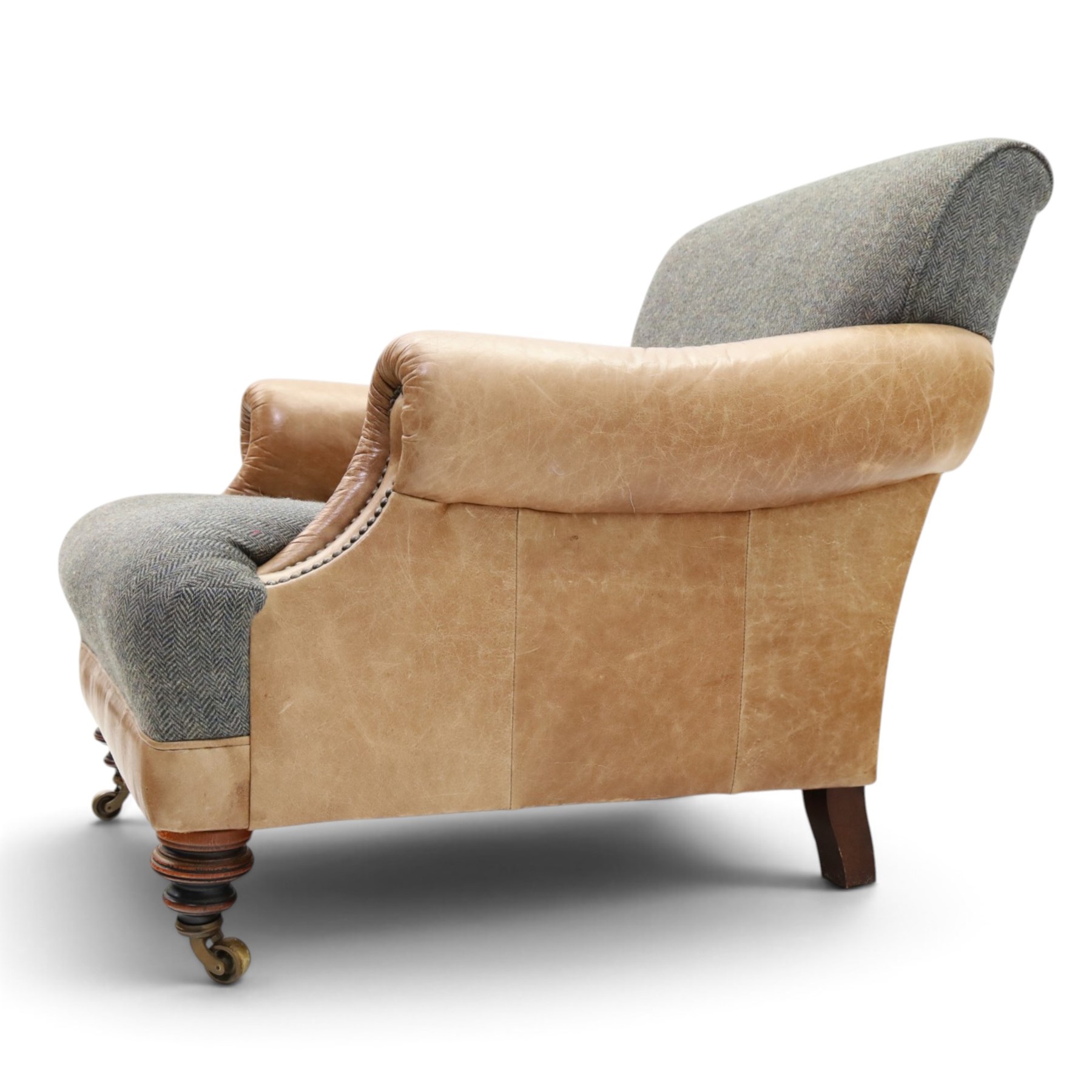 Tetrad - 'Taransay' Harris Tweed and tan leather club armchair, Howard shape with reclined back over deep seat and rolled arms with studwork, raised on turned front supports with castors, the sides and arms upholstered in tan leather with seat and back in herringbone-stitched Harris Tweed