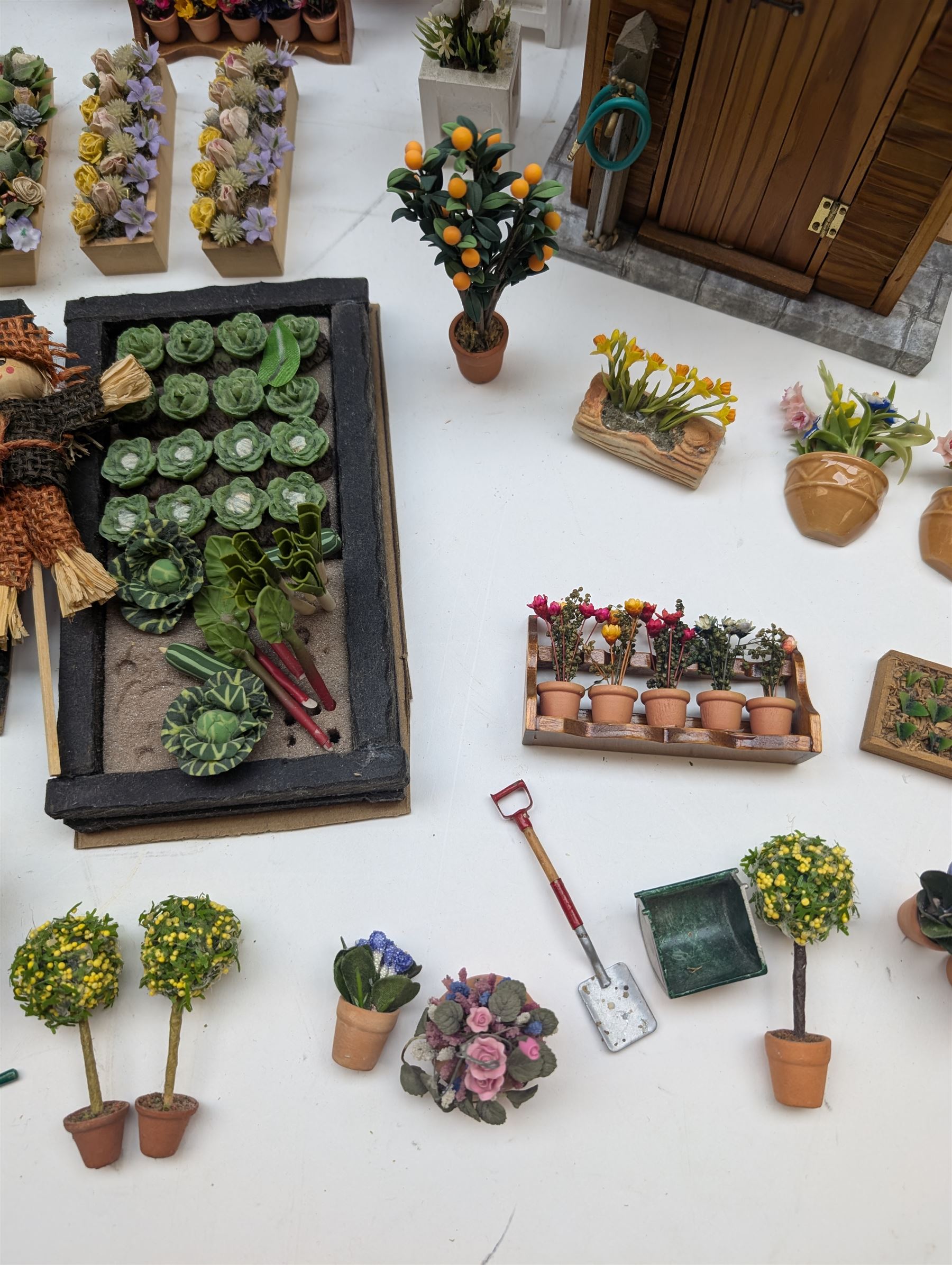 1:12 scale dolls house allotment and garden accessories, including wooden shed on a stone effect base, two vegetable patches, terracotta plant pots with flowers and foliage, stone effect plant pots, other planters, loose sunflowers, scarecrow, rabbit hutch, garden tools, fencing panels, etc 
