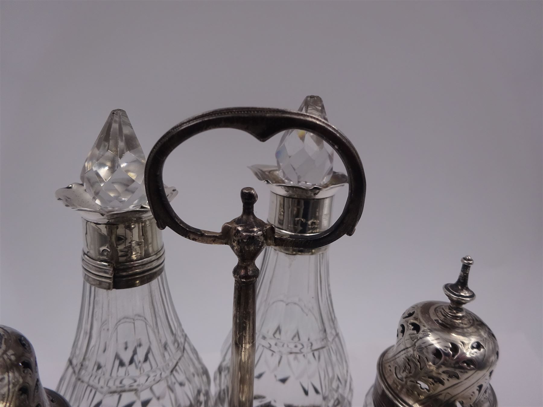 Late 18th century silver cruet stand, of oval form, with pierced sides upon four bun feet, hallmarked to handle Hester Bateman, all other hallmarks indistinct, together with five matched silver mounted cut glass cruet bottles, including some later Victorian examples, hallmarks predominantly indistinct, stand H20cm