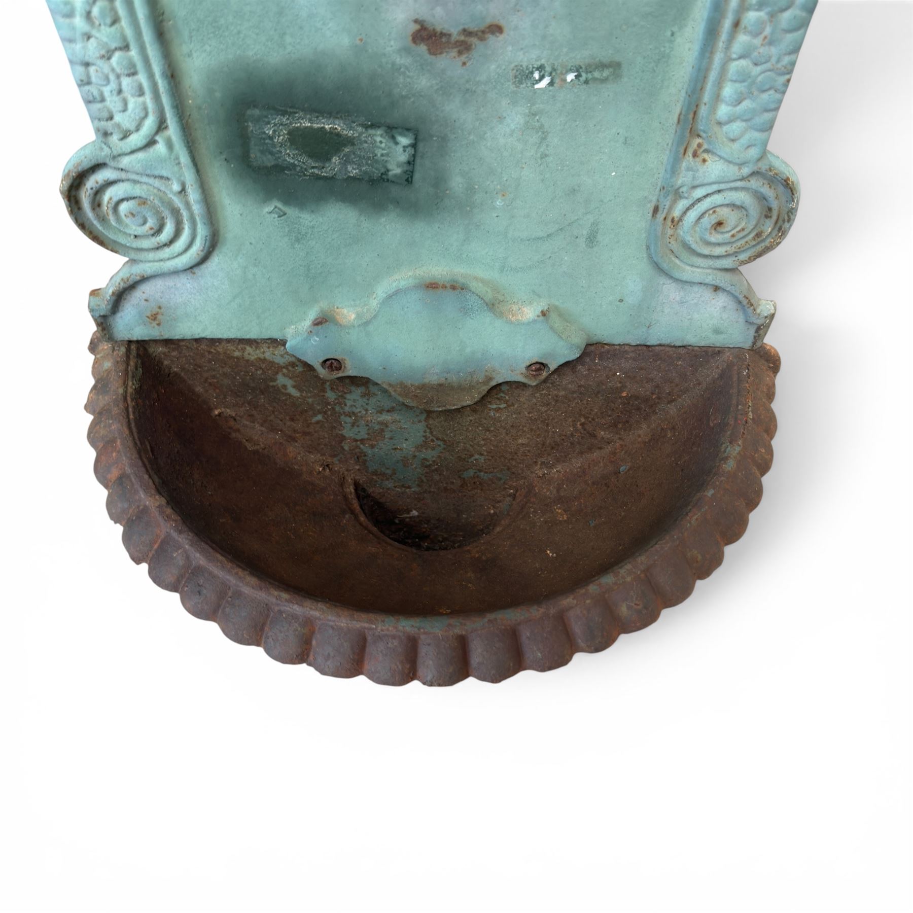 Antique cast iron wall fountain, cartouche cresting rail over a lion mask spout, with scroll and floral decoration over a scalloped basin, in rustic turquoise painted finish with rusted patina