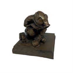 Bronzed cold cast figure of a miner sat beside a lamp by Robert Olley on rocky square plinth base, H17cm