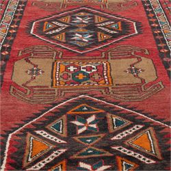 North East Persian Kurdie runner, the red field decorated with three serrated diamond medallions alternating with four ochre hooked motifs enclosing polychrome cruciform panels, within multiple geometric borders of repeating triangles and diamond devices