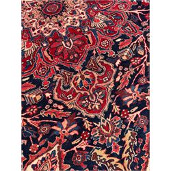 Persian Hamadan indigo and red ground carpet, large central medallion decorated with projecting palmette motifs, the surrounding field decorated with trailing branches and flower heads, crimson ground border decorated with stylised plant motifs, within floral pattern guard stripes 