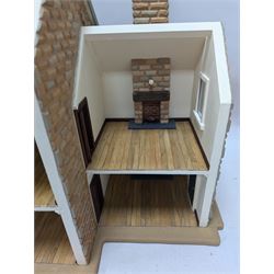 1:24 scale stone effect three-storey cottage dolls house, with green arched door and lattice effect windows, decorated to the interior with wooden floors, wired lighting and fire places, H45cm, W57cm, D26cm