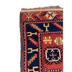 Persian red ground rug, the field decorated with multiple geometric motifs, blue band border with repeating geometric motifs