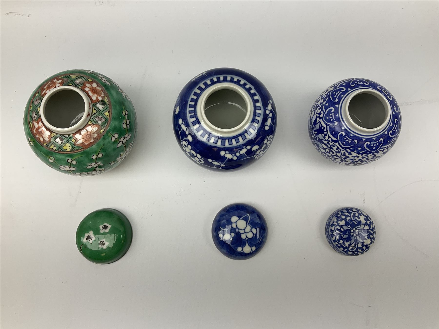 Six Chinese ginger jars, predominantly of blue and white design decorated with blossoming branches, all with lids, housed on various hardwood carved stands, some with character marks beneath