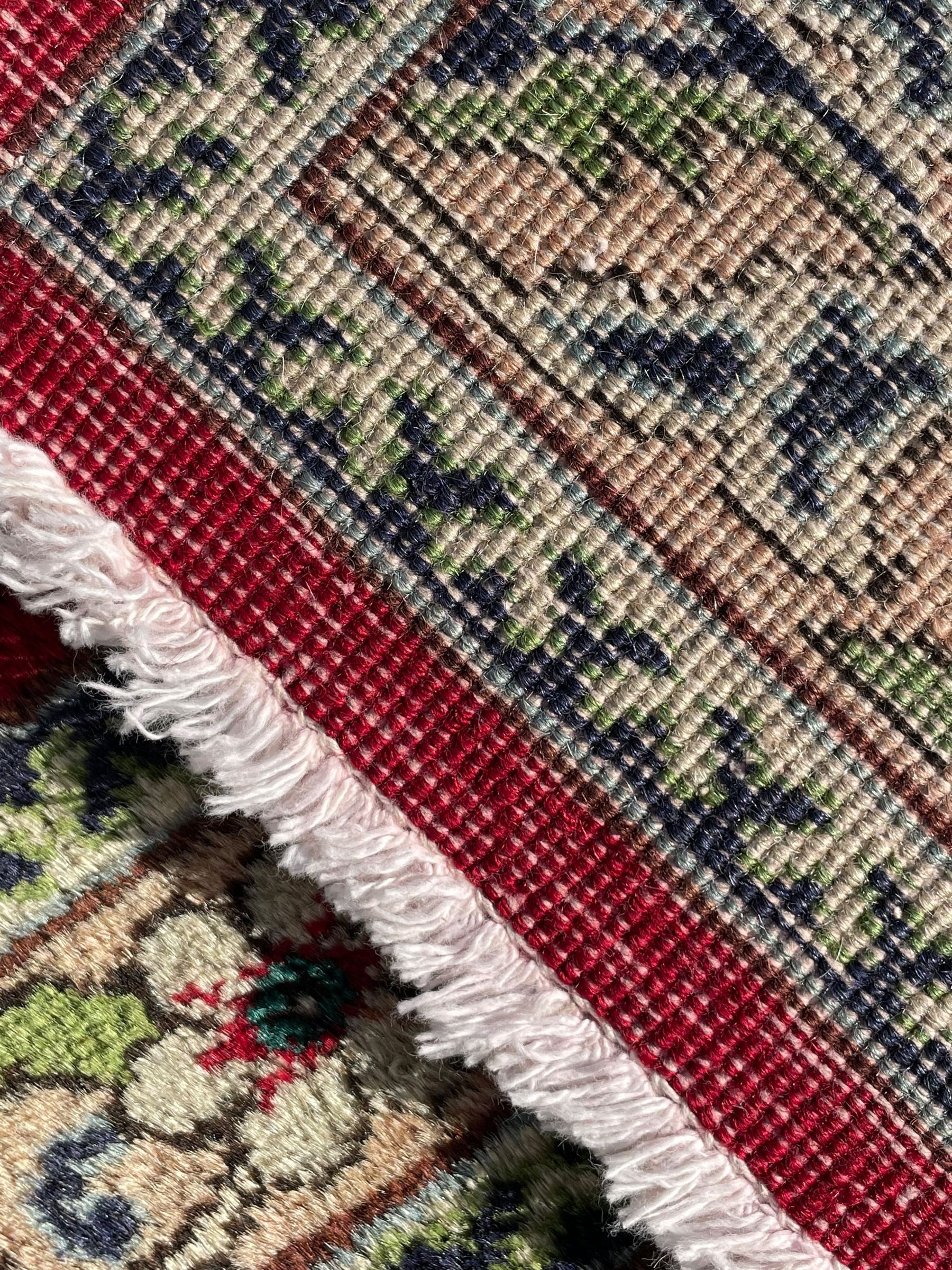 Persian Tabriz crimson ground carpet, decorated with swirling leafy branches and large palmette motifs, the pale ground border decorated with trailing foliate pattern, within floral guard stripes