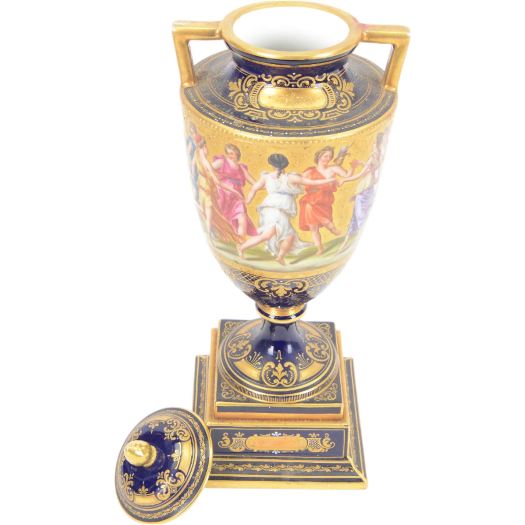 Late 19th century Vienna twin handled urn and cover decorated with classical figures on a textured gilt ground,  upon a square stepped cobalt blue pedestal with gilt detailing, H36cm