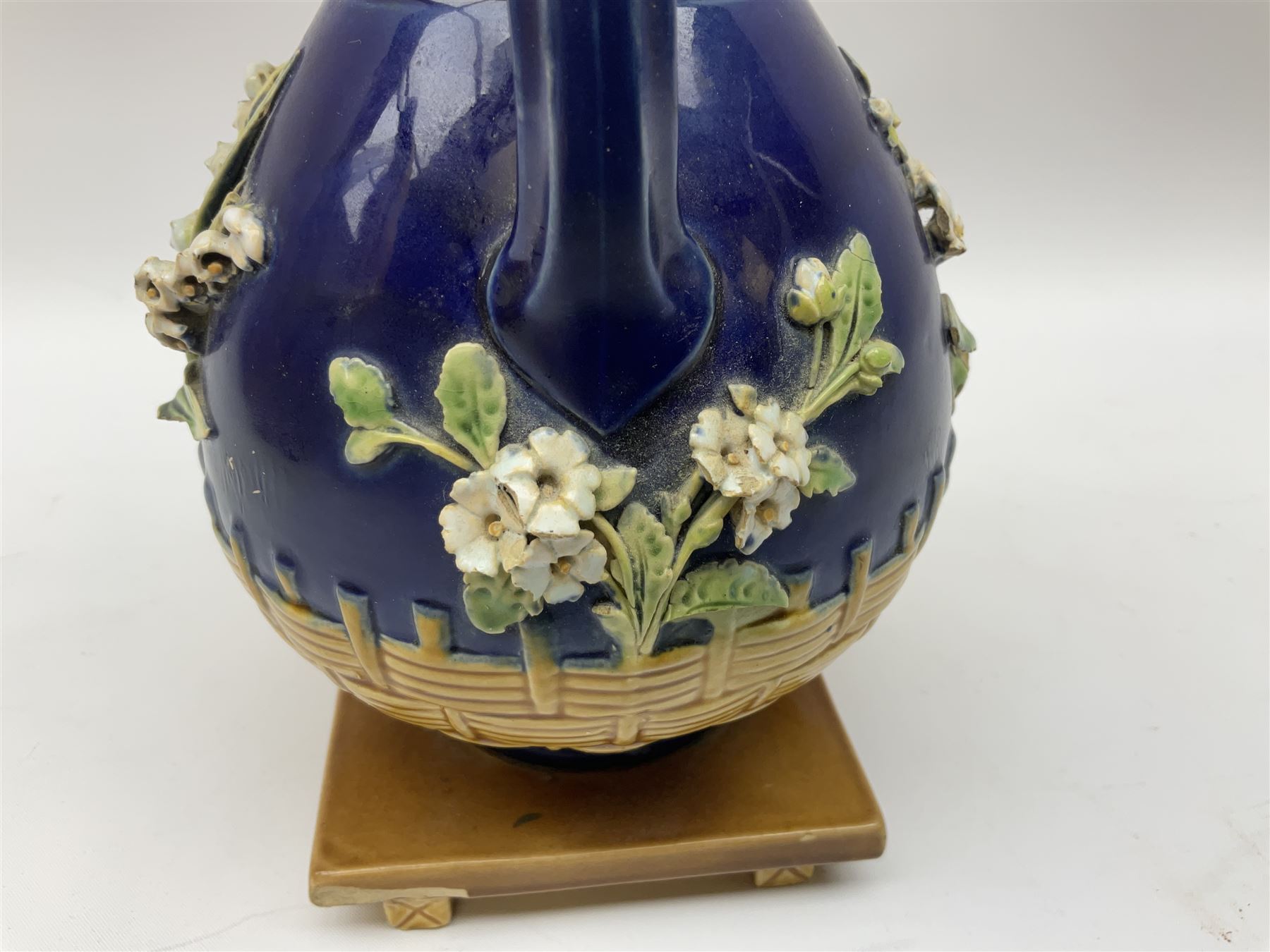 Minton majolica vase, the squat body with twin handles, with part osier moulding and applied Spring flowers against a cobalt blue ground, upon integral square base, impressed beneath Minton 1316, H16.5cm