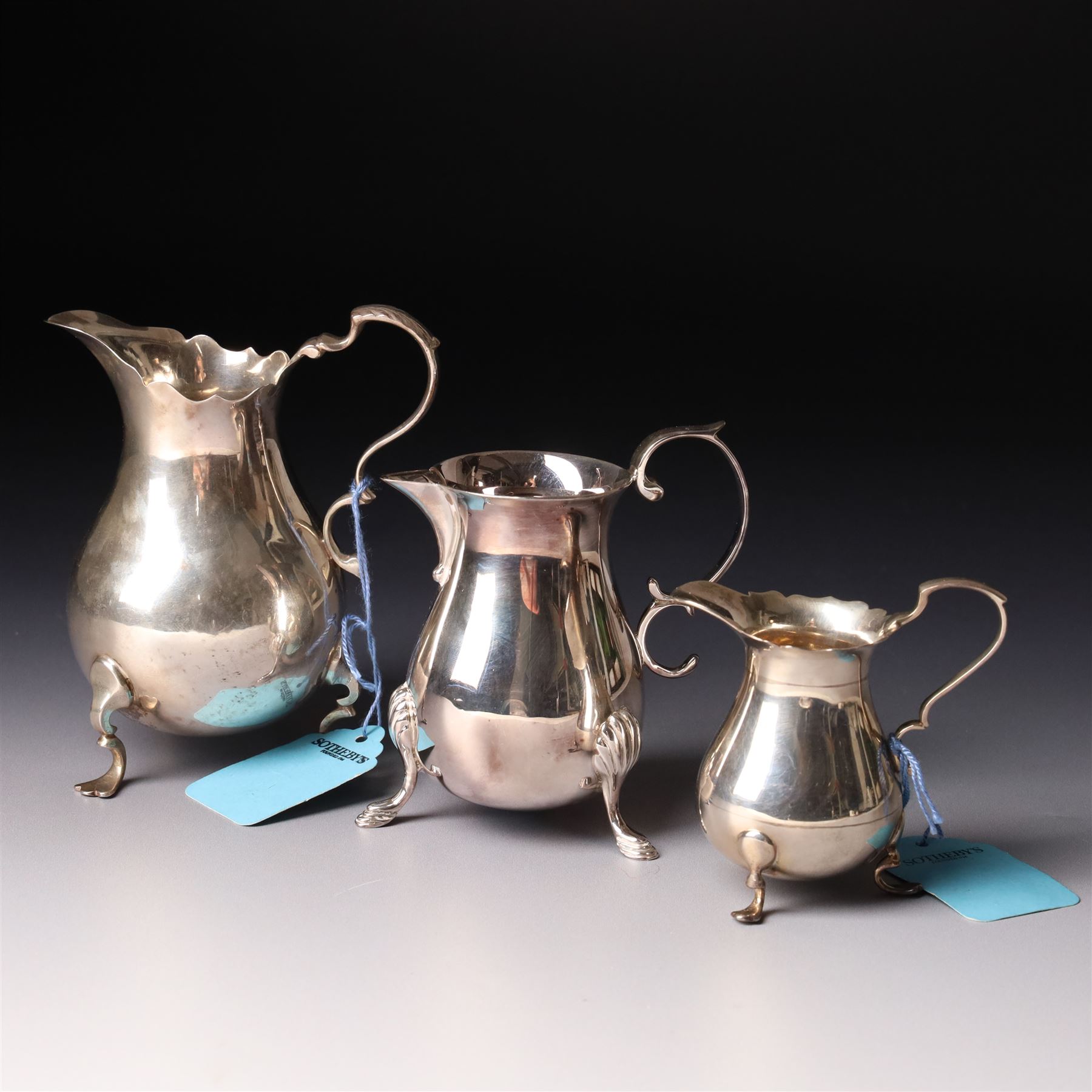 Georgian design silver cream jug with crimped rim and engraved with a crest London 1901 Maker Haseler Bros. and two smaller silver cream jugs (3)