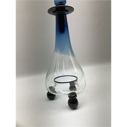 Contemporary glass fly/wasp trap by Gillies Jones of Rosedale, the catcher of bottle form with an ombre design of blue to clear supported by three black ball feet, and a large blue and black stopper with twin scroll handles and finial, signed Gillies 1997 to base, H45cm