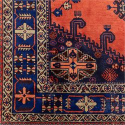Central Persian Veis hand-knotted carpet, madder red field, decorated with a repeating arrangement of large octagonal and diamond medallions filled with stylized cross and geometric motifs and angular tribal devices within a series of geometric borders in tones of madder red, indigo blue, ivory, and soft green, with cotton fringe ends 