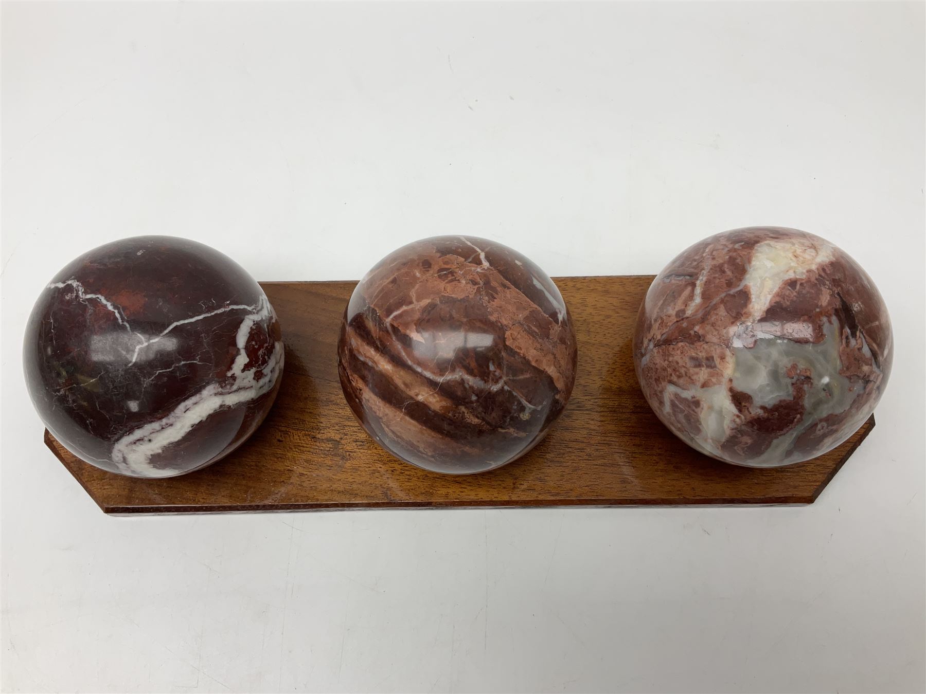 Set of three marble spheres on a elongated octagonal wooden base, H12cm