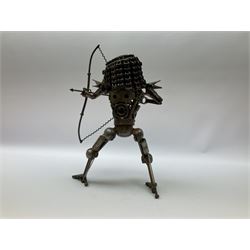 Predator metal sculpture, made with scrap metal, with articulated body, bike chain hair, and bow and arrow, H45cm