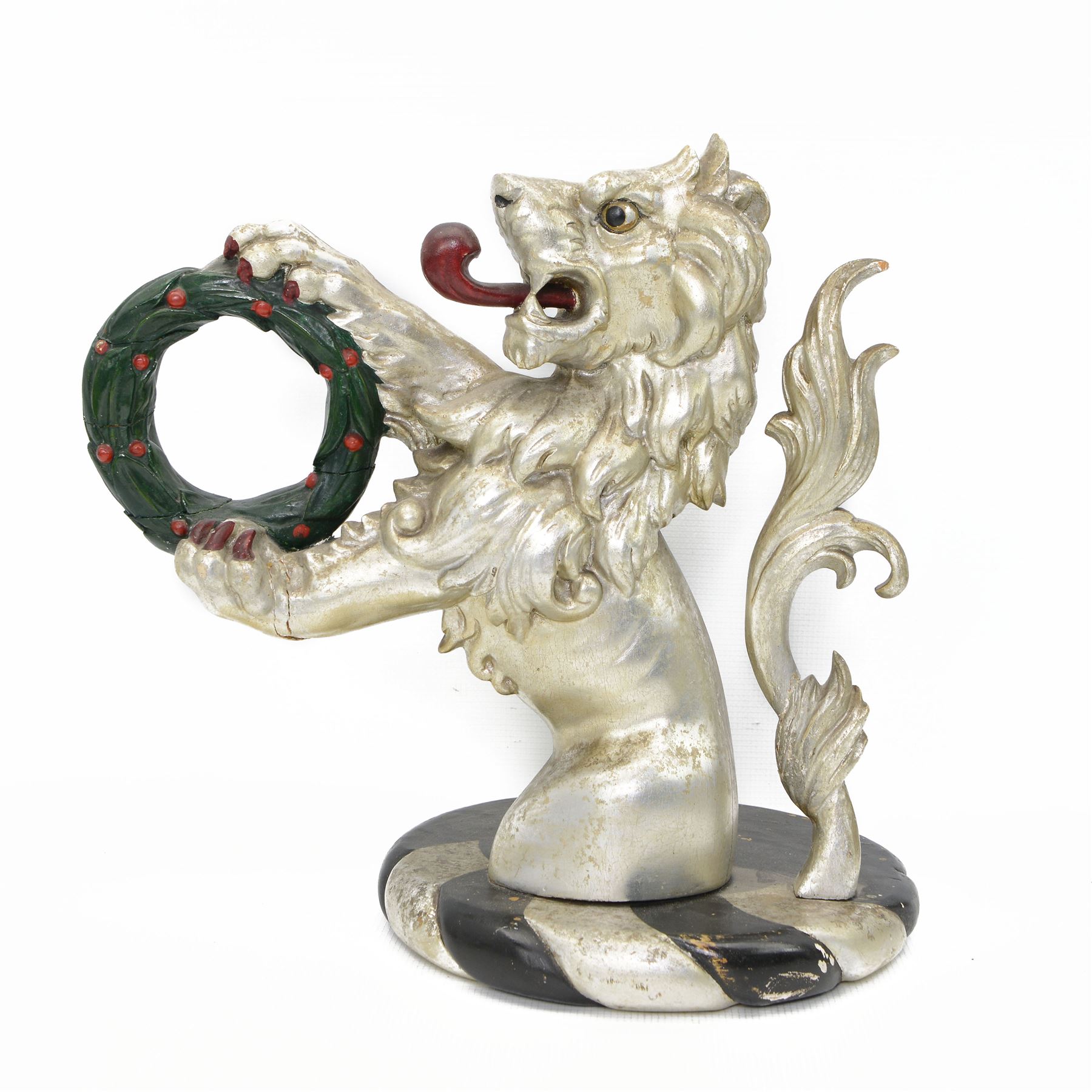 20th century carved silvered wood crest of a lion holding a wreath, possibly a horse tether, on circular wooden plinth, H37cm 