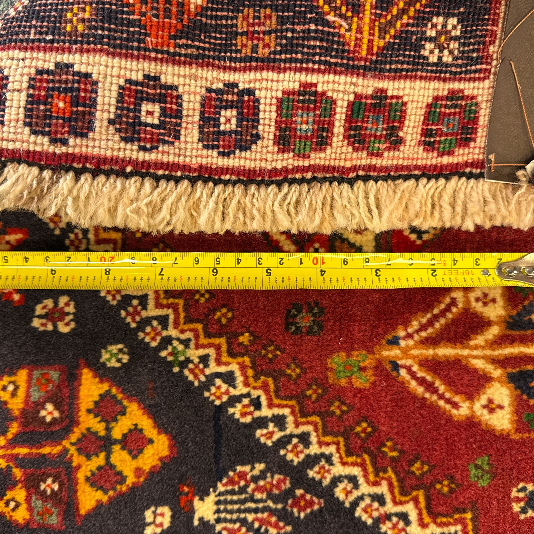 South West Persian Qashqai rug, hand knotted wool with central dark blue lozenge medallion containing geometric motifs, on a madder red field decorated with stylised floral boteh motifs, indigo spandrels, multiple borders of floral rosettes, from the region of Fars, south-west Persia