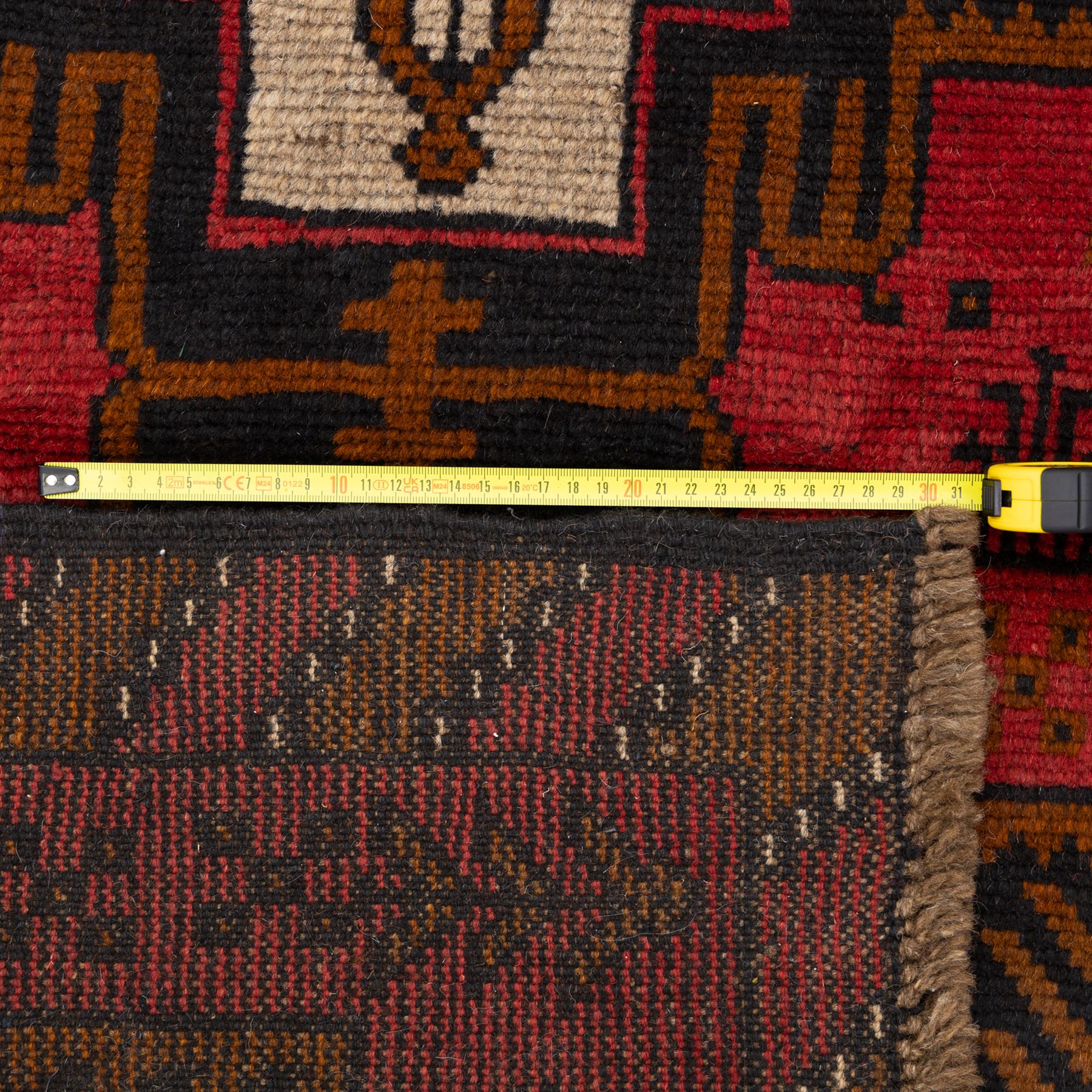 Turkish Anatolian rug, crimson ground, with stepped geometric medallions in ivory, brown, and black within angular striped borders in tones of red and ochre 