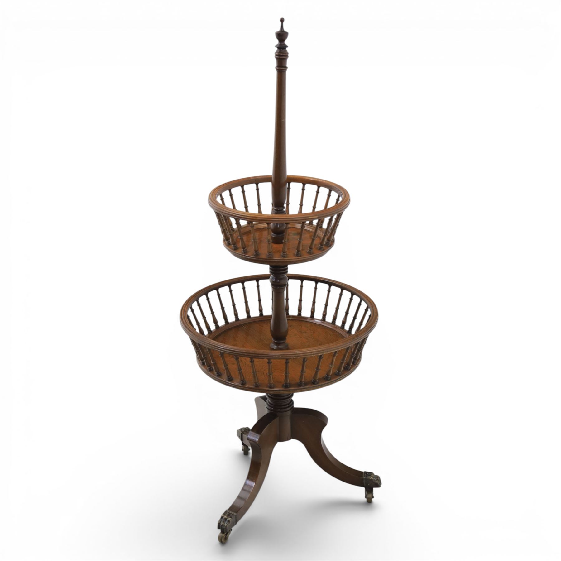 Regency style oak two-tier dumb waiter, with turned finial above central column support, two circular spindle-galleried basket tiers, raised on downswept tripod supports with brass caps and castors