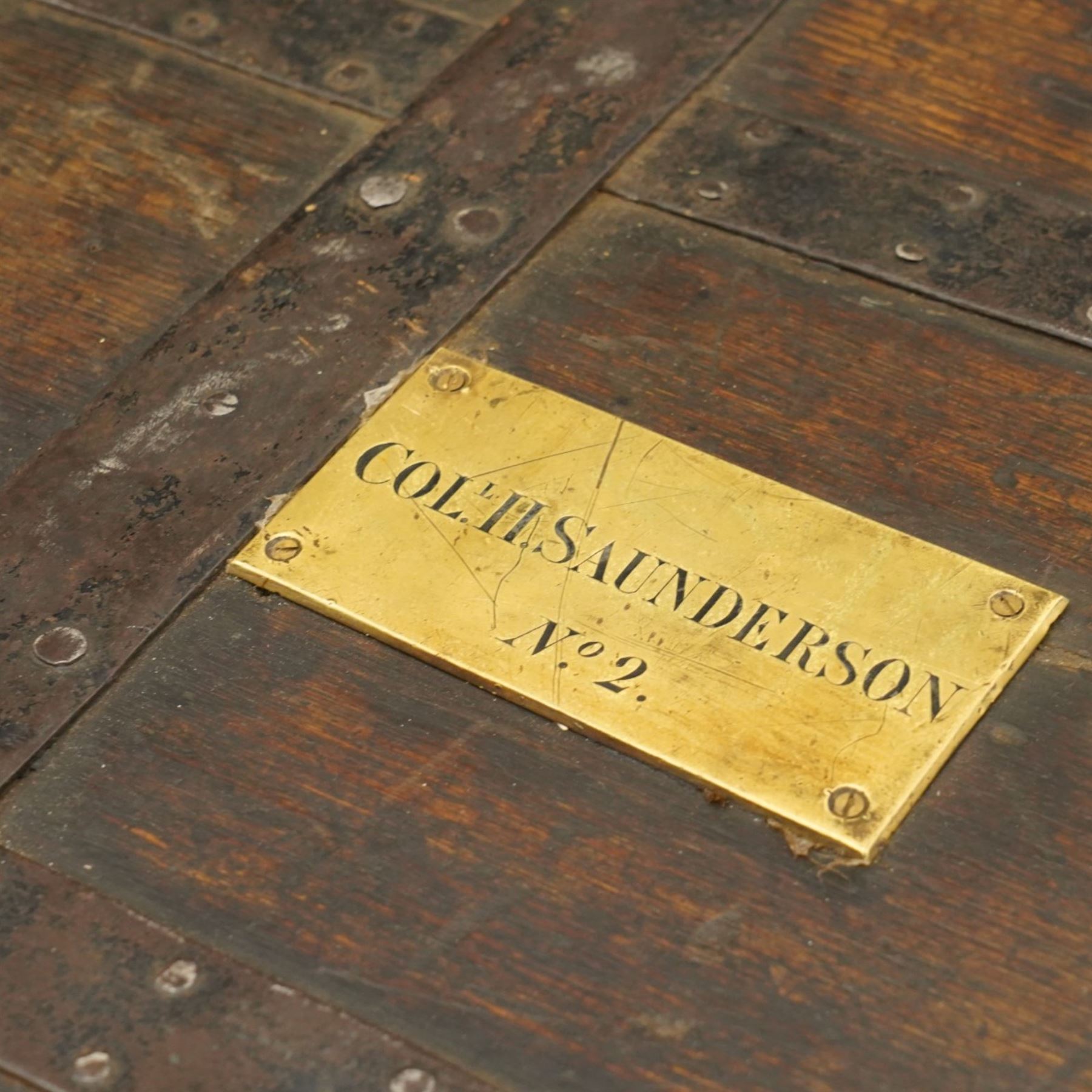 Early 19th century oak and wrought metal bound plate chest, the hinged lid with an engraved brass plaque inscribed Col H Saunderson No.2, enclosing a vacant interior, with metal carrying handles to the sides and pivoting clasp