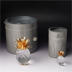 Pair of Swarovski Crystal candlesticks, boxed, together with two paperweights in the form of pineapples with gilt mounts, a large and small example, boxed (4)