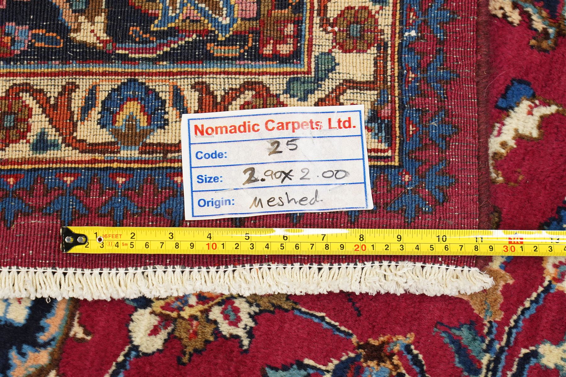 Central Persian Kashan hand-knotted carpet, rose red field, with central shaped lobed medallion issuing an all-over scrolling design of palmettes, floral sprays and arabesques, within conforming spandrels, enclosed by a broad indigo herati type palmette border framed by multiple guard stripes, in a palette of deep red, midnight blue and ivory tones, with cotton fringe ends, and Kashan signature 