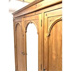 Gothic triple pine wardrobe, projecting cornice, central cupboard door with bevelled edge mirror, flanked by two cupboard doors 
enclosing shelving and hanging rail, above three short and two long drawers, shaped plinth base