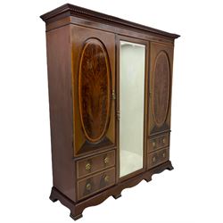 James Shoolbred & Co. London - Edwardian inlaid mahogany triple combination wardrobe, projecting dentil cornice over bevel glazed door, two figured oval panelled doors and four drawers, the central compartment fitted with linen slides and drawers, satinwood banding, on base with shaped apron and bracket feet, with enamel plaque 