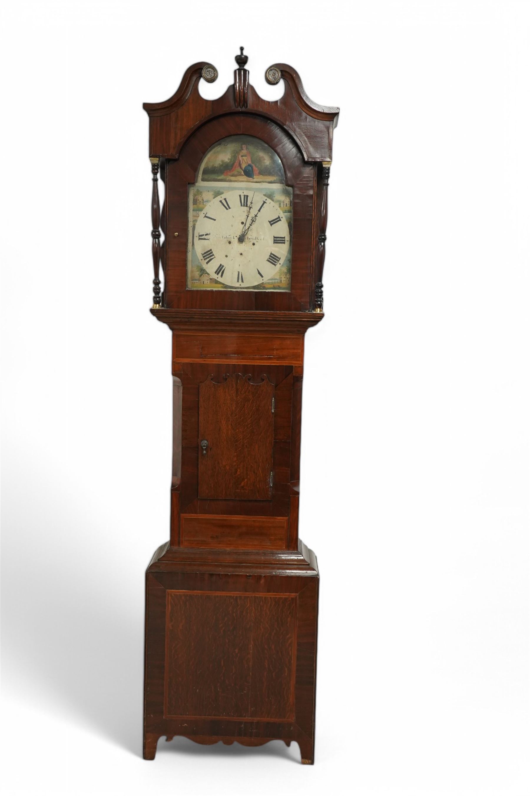 William Brooksbank of Bradford - late oak and mahogany 30-hour 19th century longcase clock c1860, with a swan necked pediment and turned wooden +finial, with a break arch hood door flanked by bobbin turned pilasters, trunk with canted corners and a short trunk door on a broad plinth with banding, painted dial with painted cottages to the spandrels and a depiction of a country girl to the arch, with broad Roman numerals, makers name and stamped brass hands, dial pinned to a chain driven countwheel movement striking the hours on a bell. With weight and pendulum.
William Brooksbank is recorded as working from Market Street, Bradford, 1837-71.