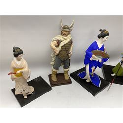 Clay Japanese Hakata dolls, comprising example modelled as a Geisha in blue kimono holding a fan, H41cm, another Geisha in pale pink kimono, H34cm, a Samurai, H35cm, and a composite figure of a Viking, H42.5cm. 