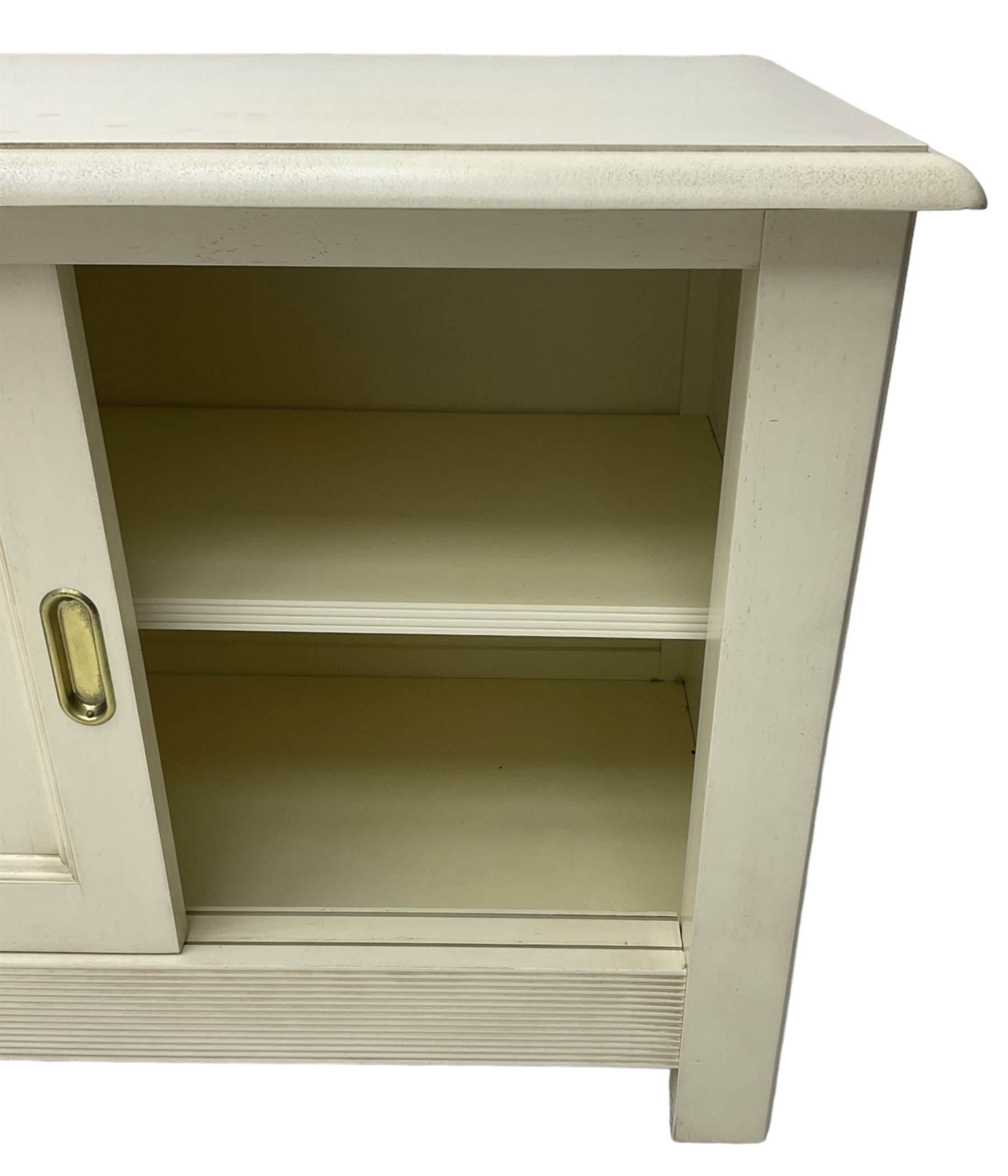 Cream finish low side cabinet, moulded rectangular top over two sliding panelled doors, on stile supports 