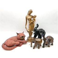 Carved wooden figure of a mother and child, H52cm, two carved wooden figures of elephants, and a further model of an elephant with leather ears, plus a doorstop modelled as a recumbent cat, in one box 