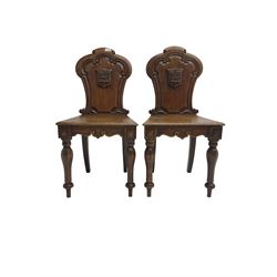 Pair Victorian oak hall chairs, scallop shaped back with carved scrolls and central shield moulding, panel seat over shaped frieze rail, raised on turned supports