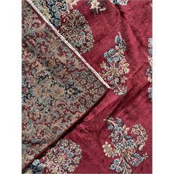 Persian Kirman carpet, the bold ruby field hosting a multi-lobed central medallion, embellished with scrolling vines and floral sprays, edged by layered borders and trimmed with short fringe