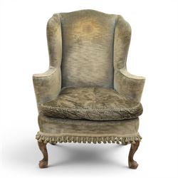 Pair of Georgian style wing armchairs, upholstered in green velvet, each with shaped wing backs, padded scroll arms and loose seat cushions, raised on cabriole supports terminating in pad feet, one with tasselled fringe