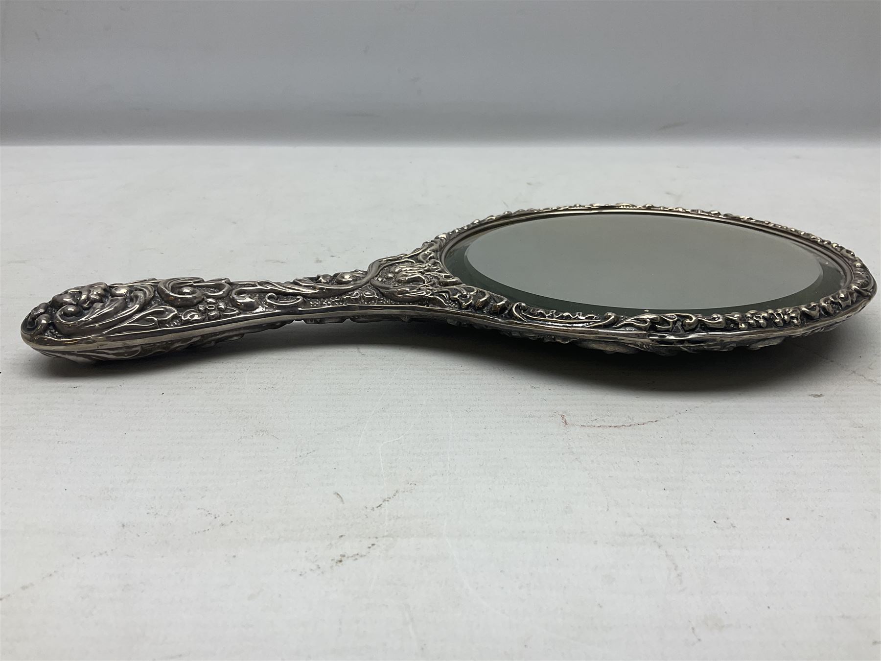 Silver mounted dressing table mirror, embossed with birds, masks, and foliate and C scrolls, hallmarked Birmingham, and fruit knife with mother of pearl handle and silver blade, (2)