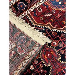 Persian Hamadan red and indigo ground rug, central lozenge medallion with extending poles, the field decorated with interlaced branches and flowerheads, guarded border with stylised floral motifs