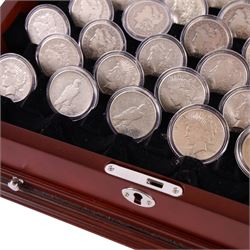 Thirty-two United States of America silver one dollar coins, comprising twenty-three 'Morgan' dollars and nine 'Peace' dollars, presented as 'The Complete Morgan and Peace Silver Dollar Collection', in display case